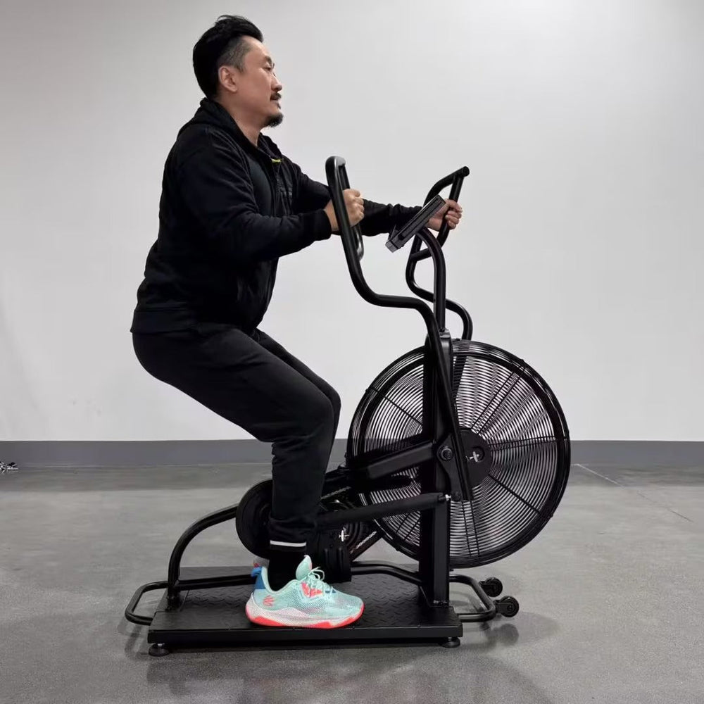 Man exercising on a black exercise bike in a gray room