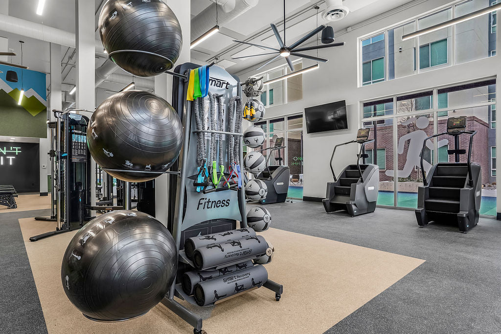 Gym interior with exercise balls and equipment in a well-lit room.