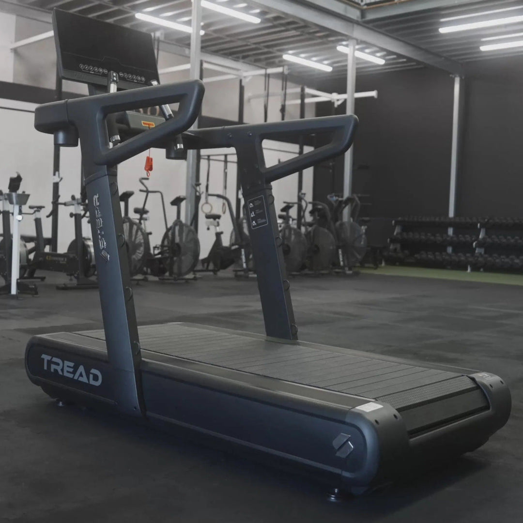 Treadmill in a gym setting with various exercise equipment in the background