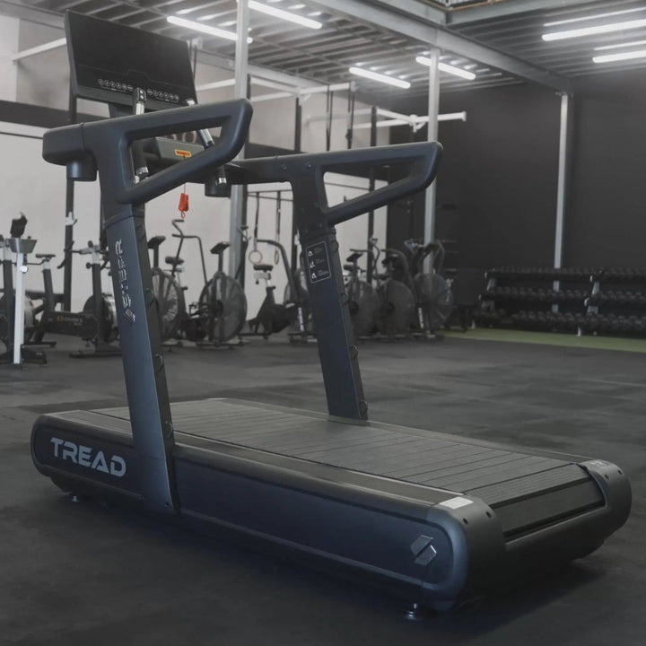Treadmill in a gym setting with various exercise equipment in the background